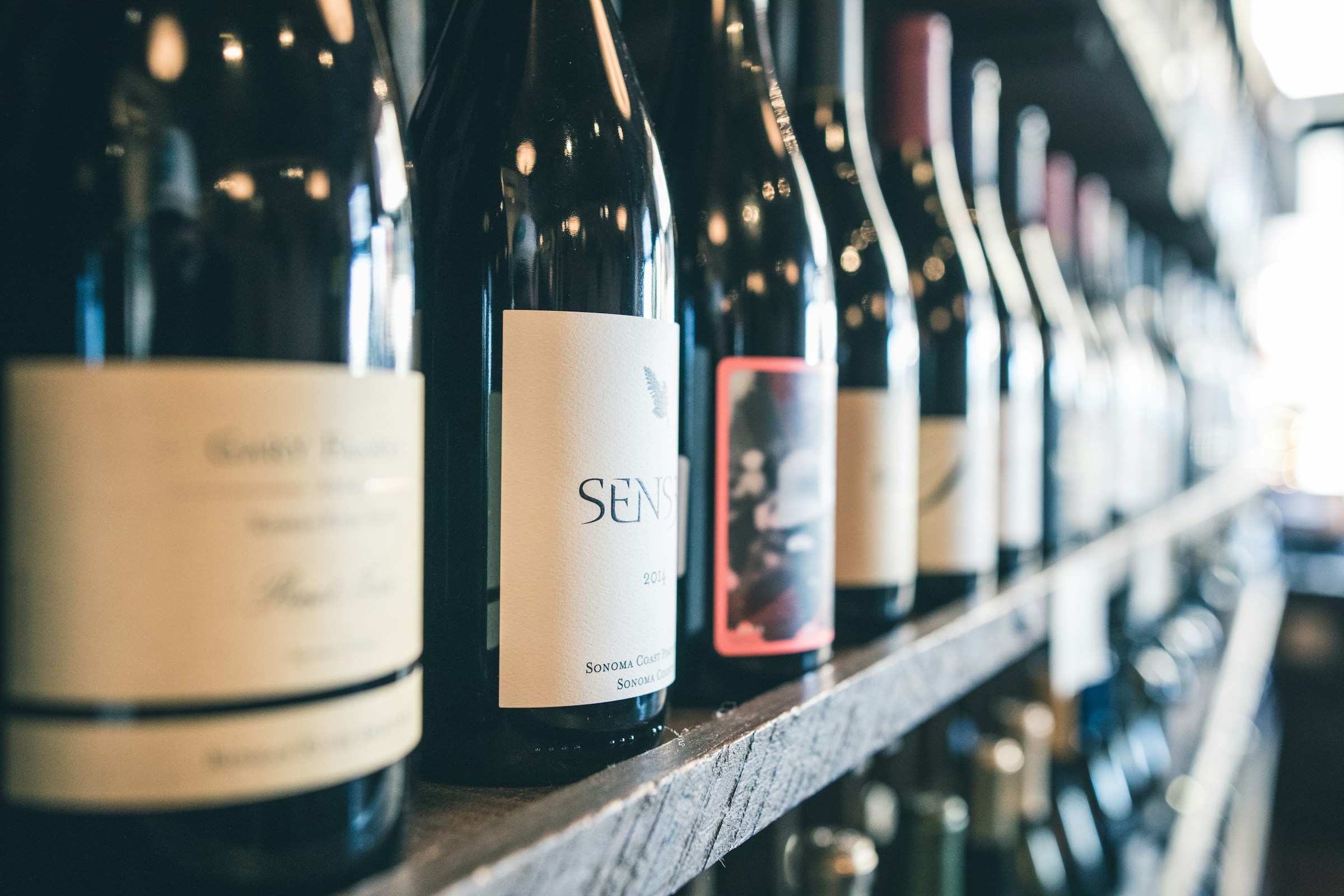 Photo of wine bottles on a shelf, by Scott Warman from Unsplash